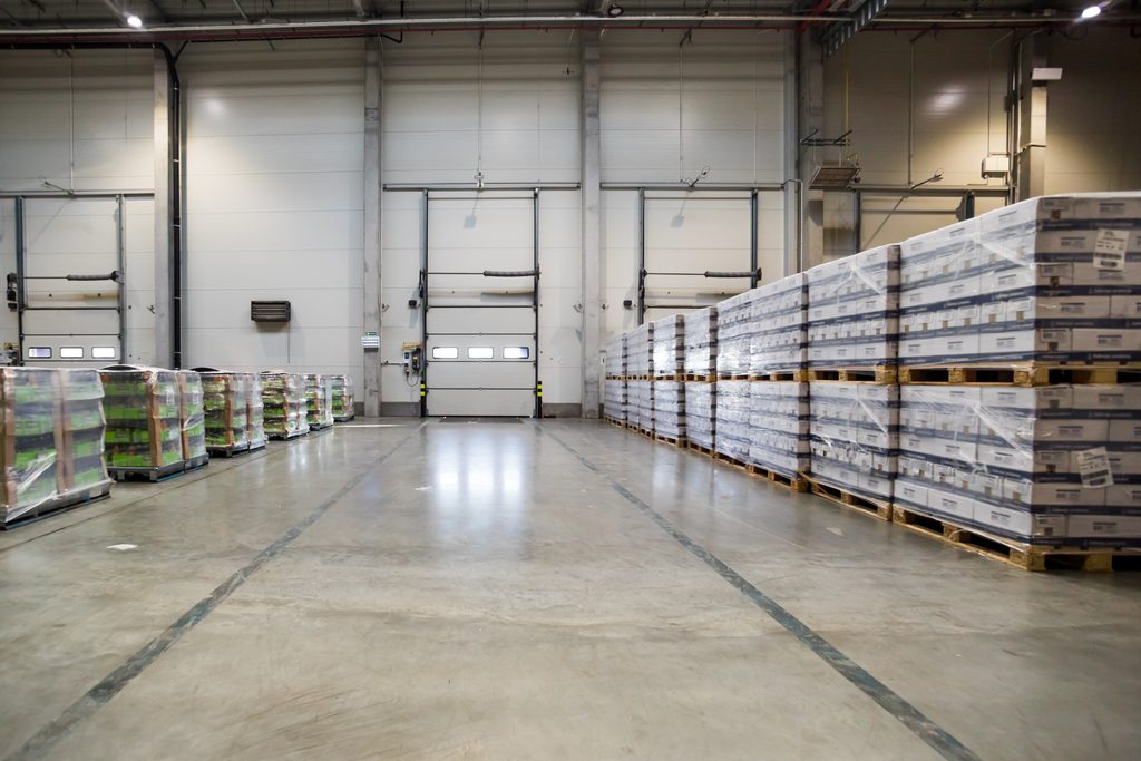 Clean warehouse floor with roll-up loading dock doors and rows of shrink-wrapped pallets